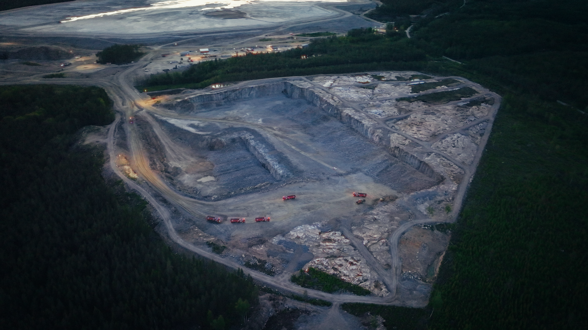 Aerial view of a quarry with 5 volvo autonomous trucks running inside them.